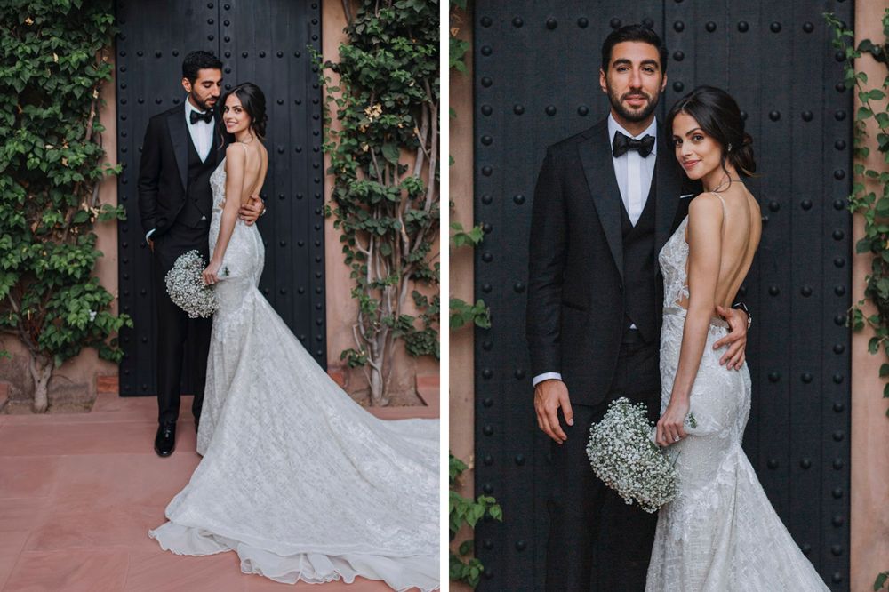 Elegant couple poses together at their wedding, with bride in backless lace gown and groom in classic tuxedo.