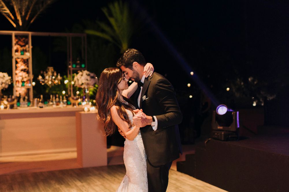 Newlywed couple shares an intimate moment during their first dance at an evening outdoor reception.