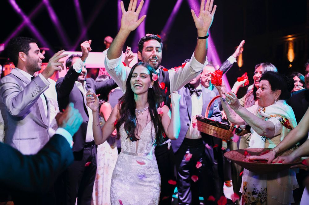 Wedding celebration with a crowd of guests dancing and celebrating at a lively reception with purple lighting effects.