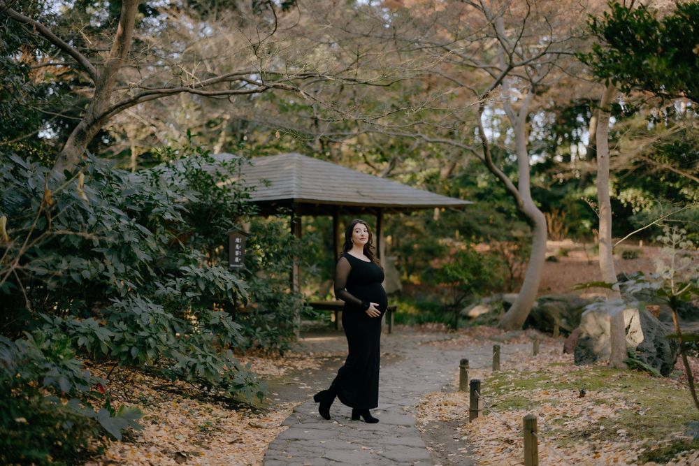 A serene garden path with a traditional Japanese umbrella and elegant black attire amid autumn foliage.