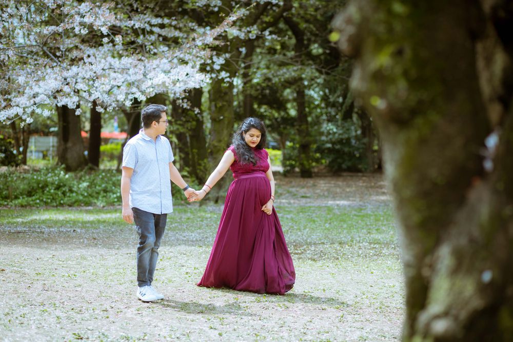 Couple walking hand in hand through cherry blossom garden path.