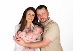 Studio portrait of happy family with newborn against white background.