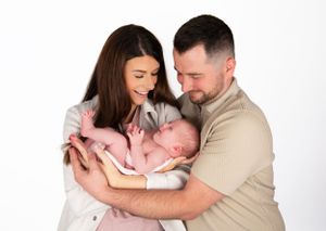 Intimate family portrait with newborn in studio against white background.