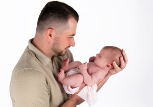 Tender moment between parent and newborn in studio setting.