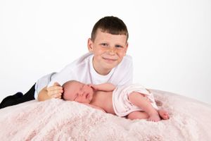 Sweet portrait of siblings bonding together on pink blanket.