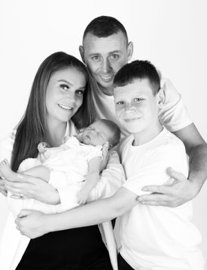 Black and white portrait of a modern family posing together against white background.