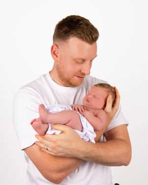 Gentle moment between parent and sleeping newborn in studio setting.