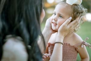 A gentle moment of connection between a child and parent during a tender outdoor interaction.
