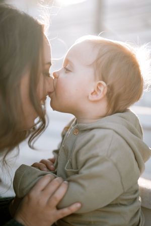 A tender moment between a parent and child backlit by soft natural light against a light-colored background.