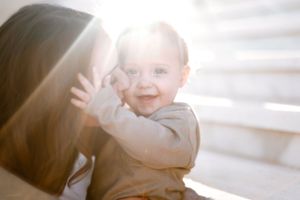 A sequence of intimate family moments shot on white bedding with soft natural light creating a dreamy atmosphere.