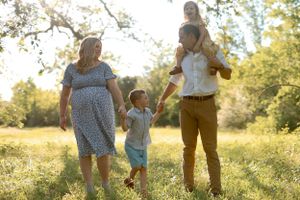 A family plays together in a sun-dappled meadow during golden hour, creating a joyful outdoor moment.