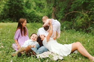 A joyful family moment together in a spring meadow filled with wildflowers and lush greenery.
