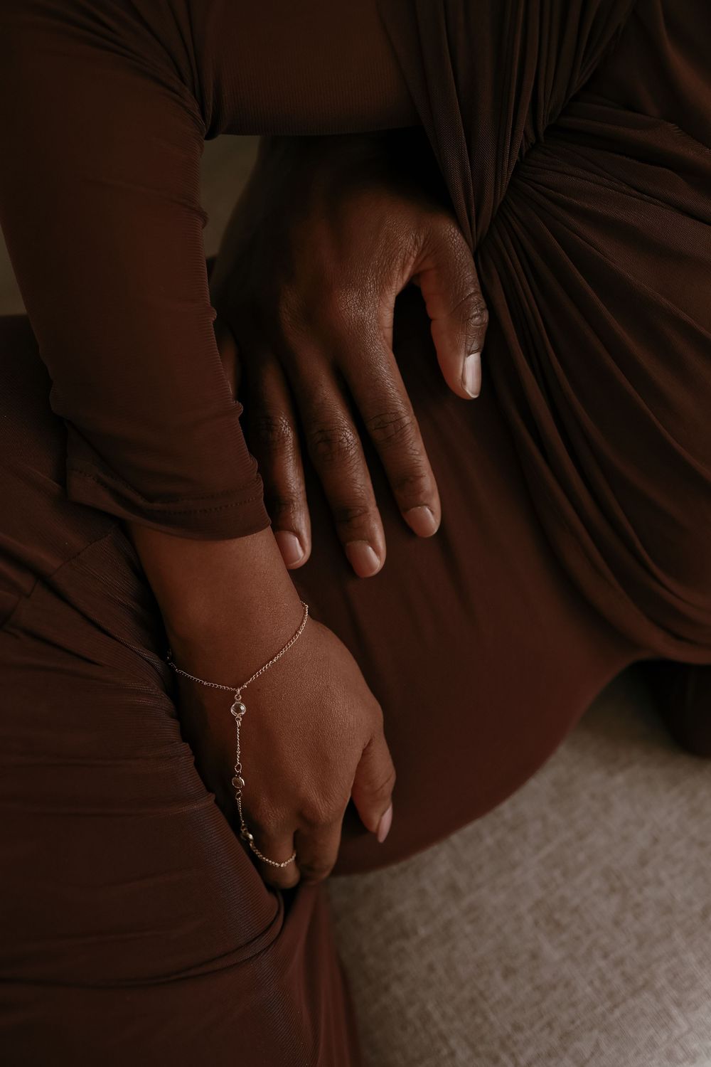 Close-up shots of hands with rings and jewelry against a dark brown fabric background.