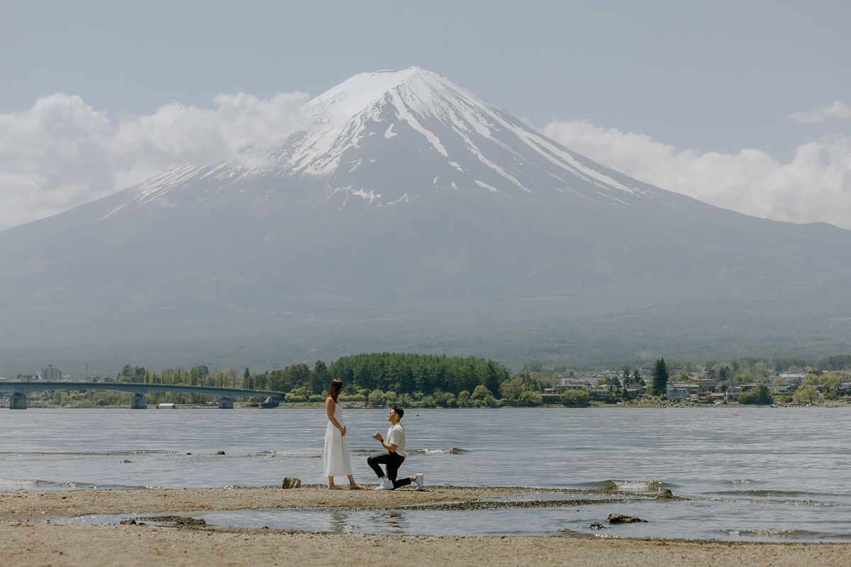 A proposal scene unfolds on a beach with majestic Mount Fuji in the background.