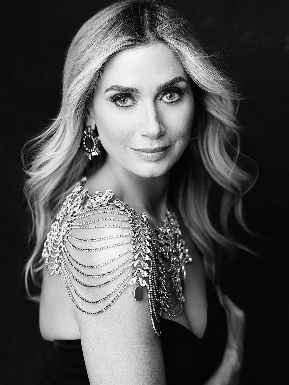 Glamorous black and white headshot featuring sparkling shoulder jewelry and wavy blonde hair. 40 over 40 fashion inspired photoshoot near me