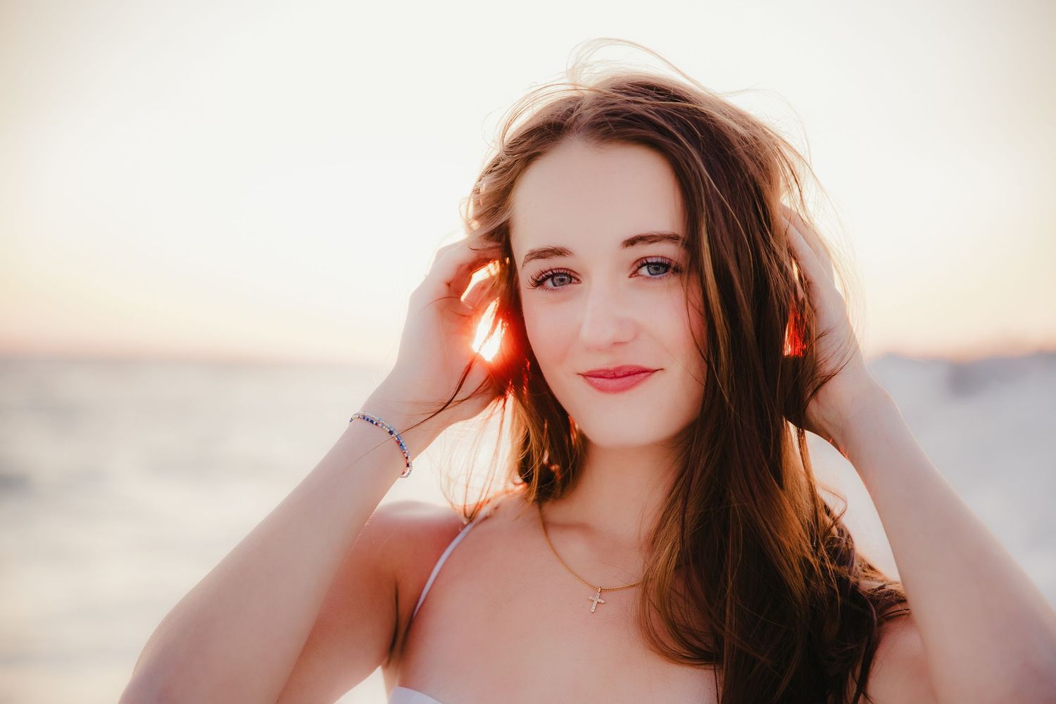 A beachside portrait at sunset wearing orange headphones.