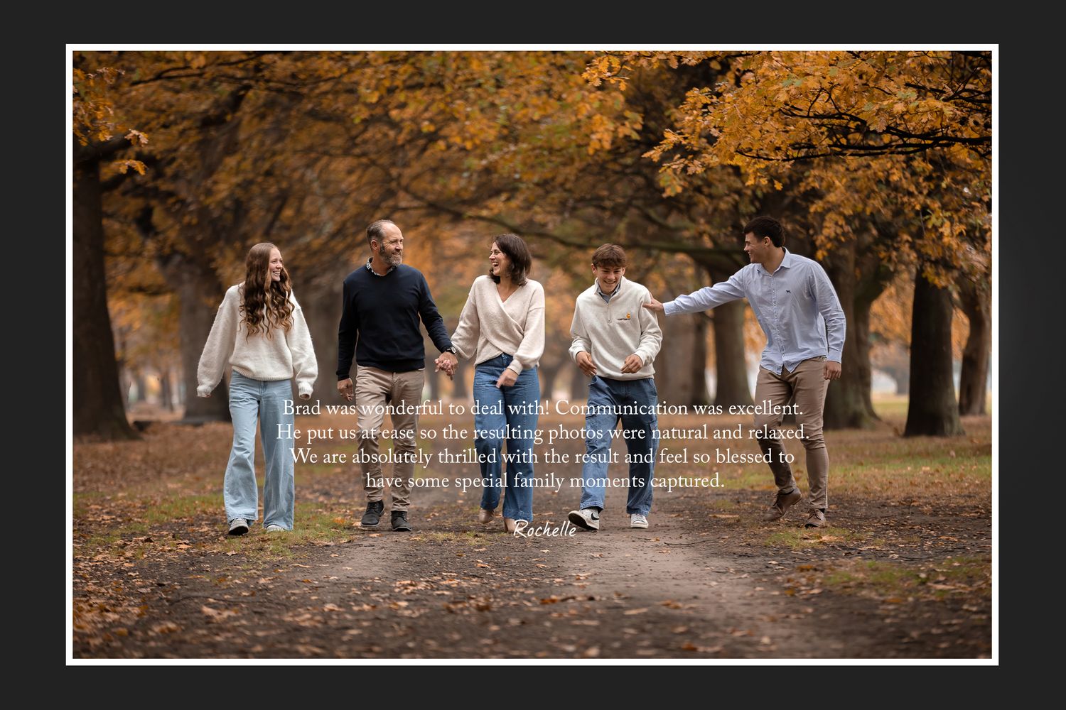 Friends walk together laughing on a path lined with autumn trees.