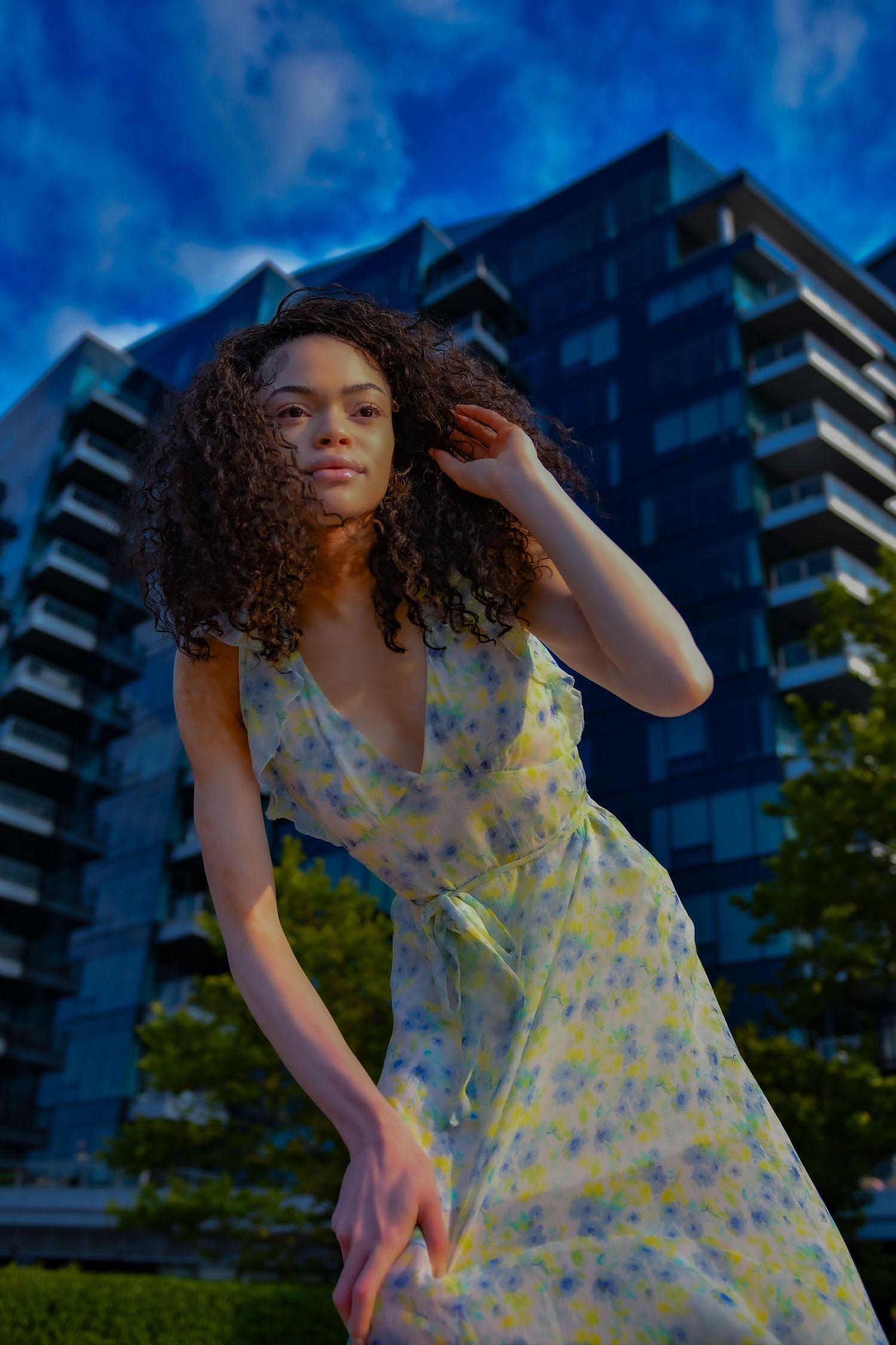 Twilight fashion portrait in floral dress with modern architecture backdrop.