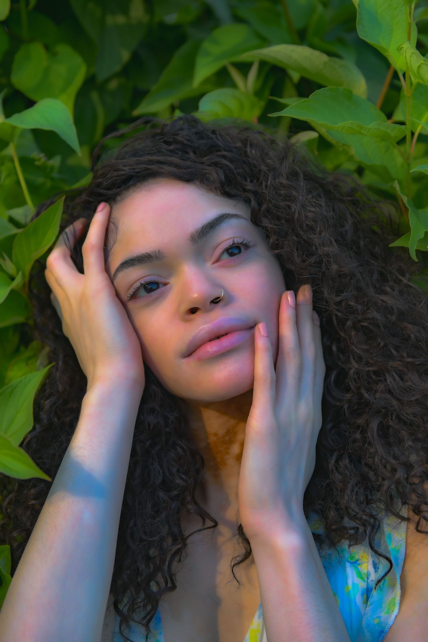 Artistic portrait surrounded by lush green foliage in natural lighting.