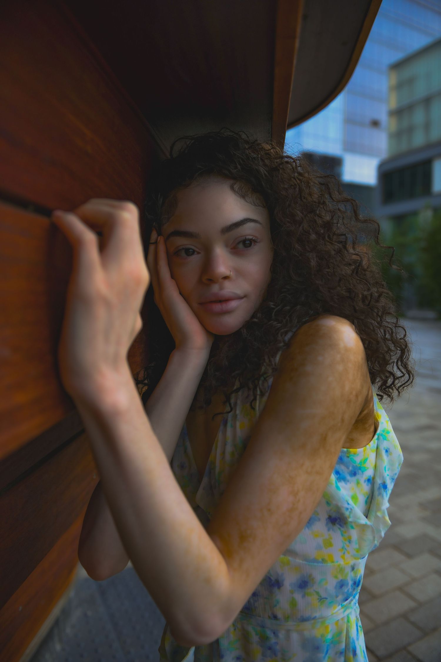 Artistic portrait against wooden wall wearing summer floral dress.