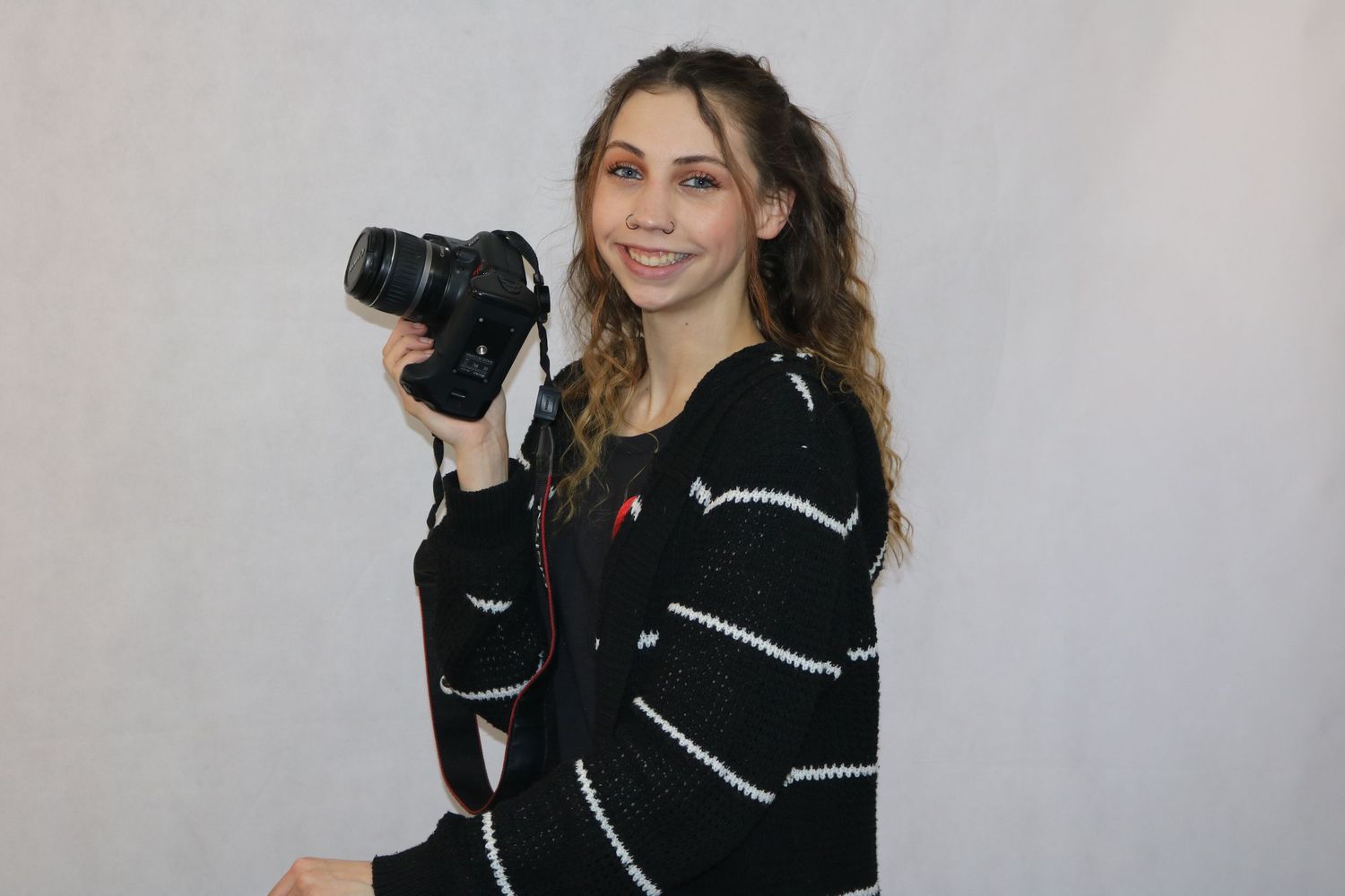 Photography branding of woman smiling holding a camera.