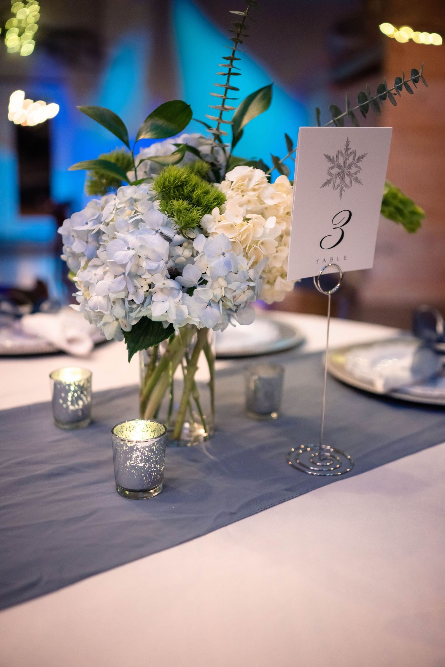 Elegant table settings with white floral centerpieces and numbered cards for a formal event.