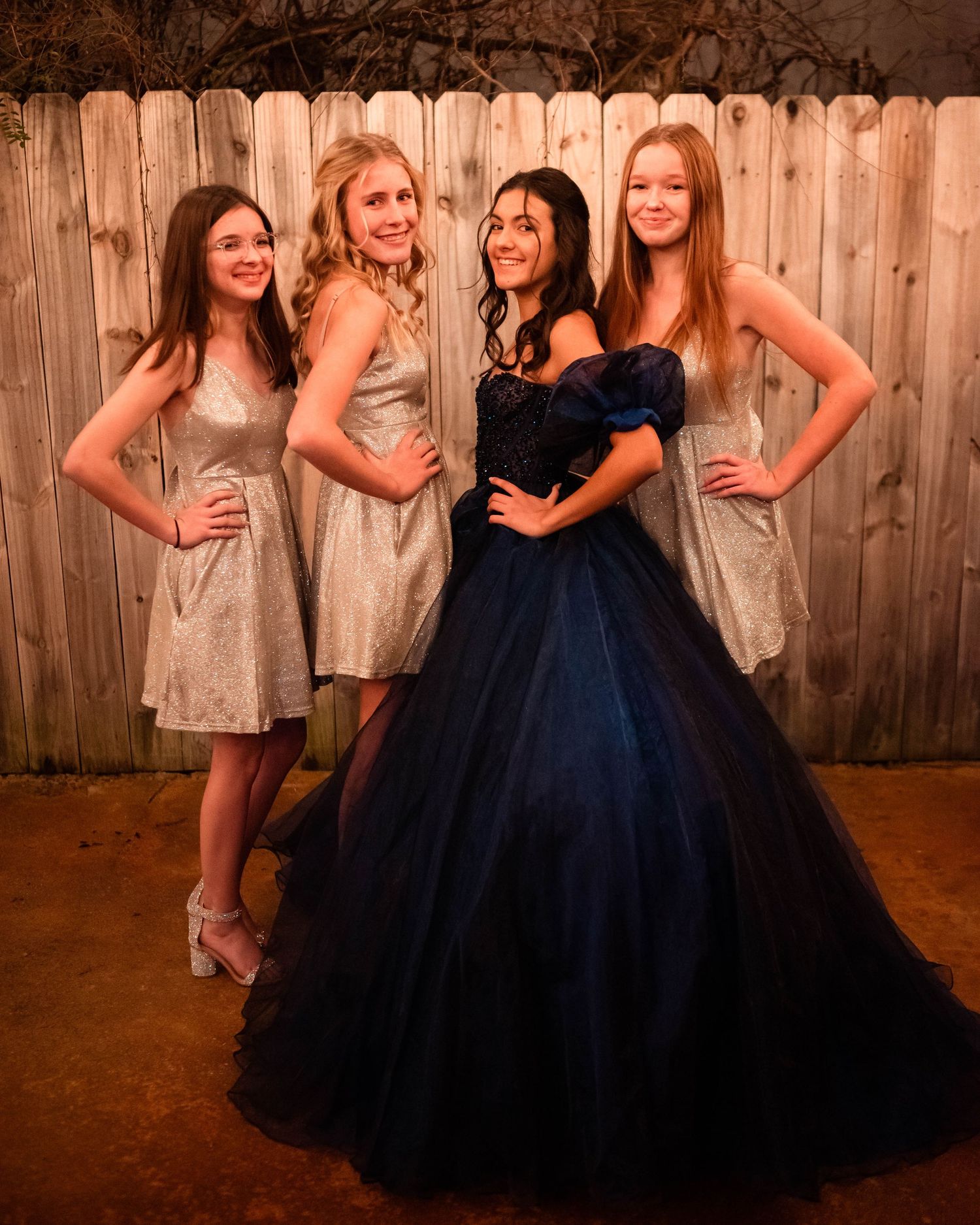 Wedding party in navy and cream dresses poses together against wooden backdrop.