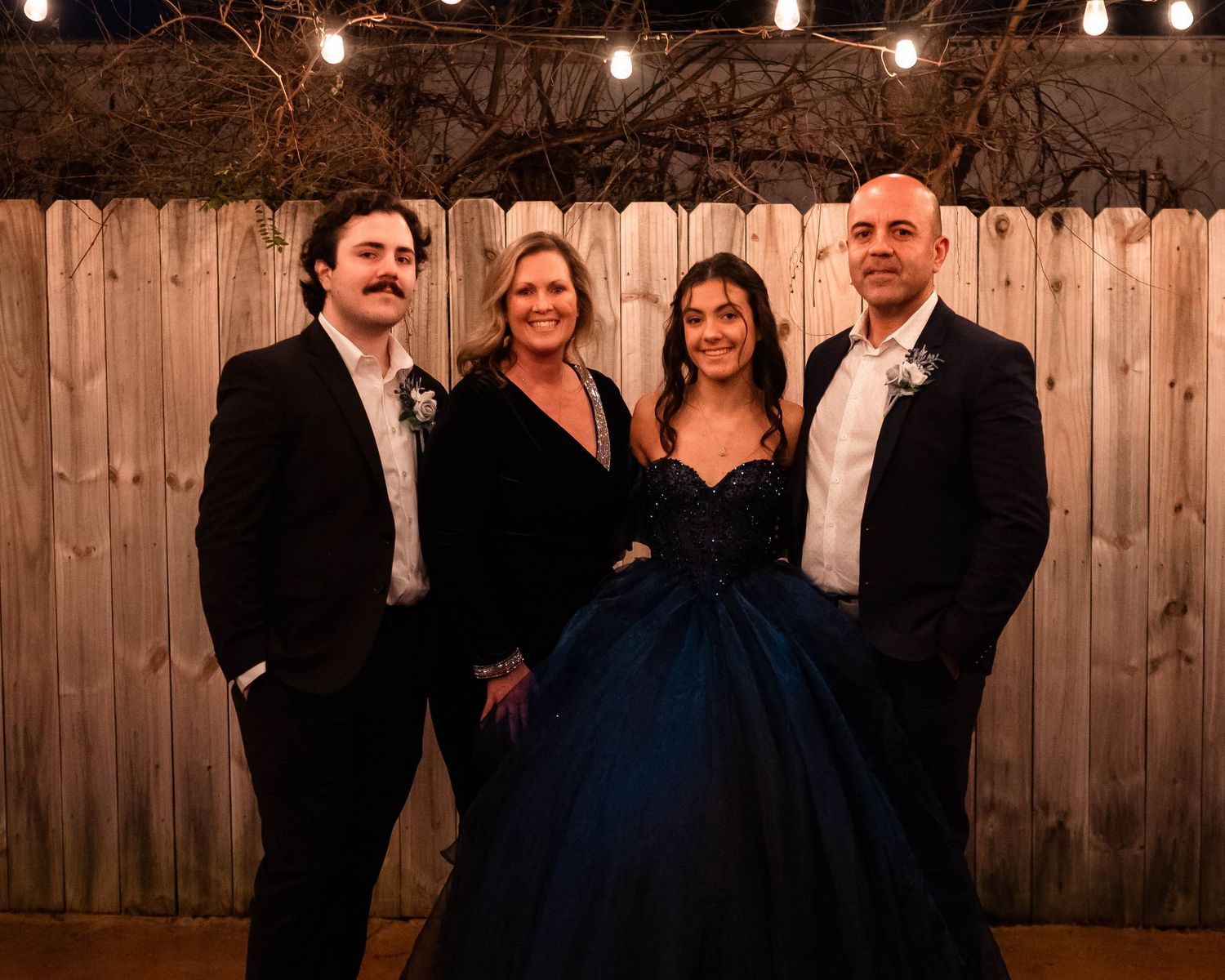 Group celebration photo with string lights and wooden fence creating cozy ambiance.