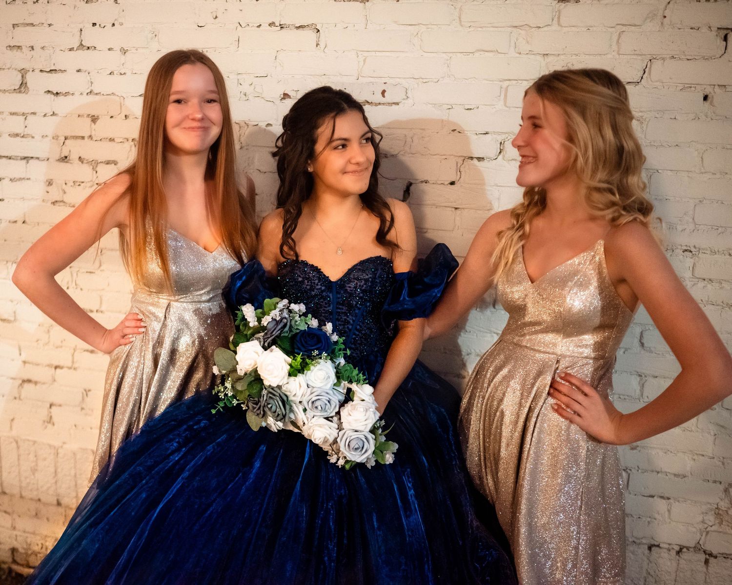 Group photo against white brick wall featuring navy and cream formal attire.