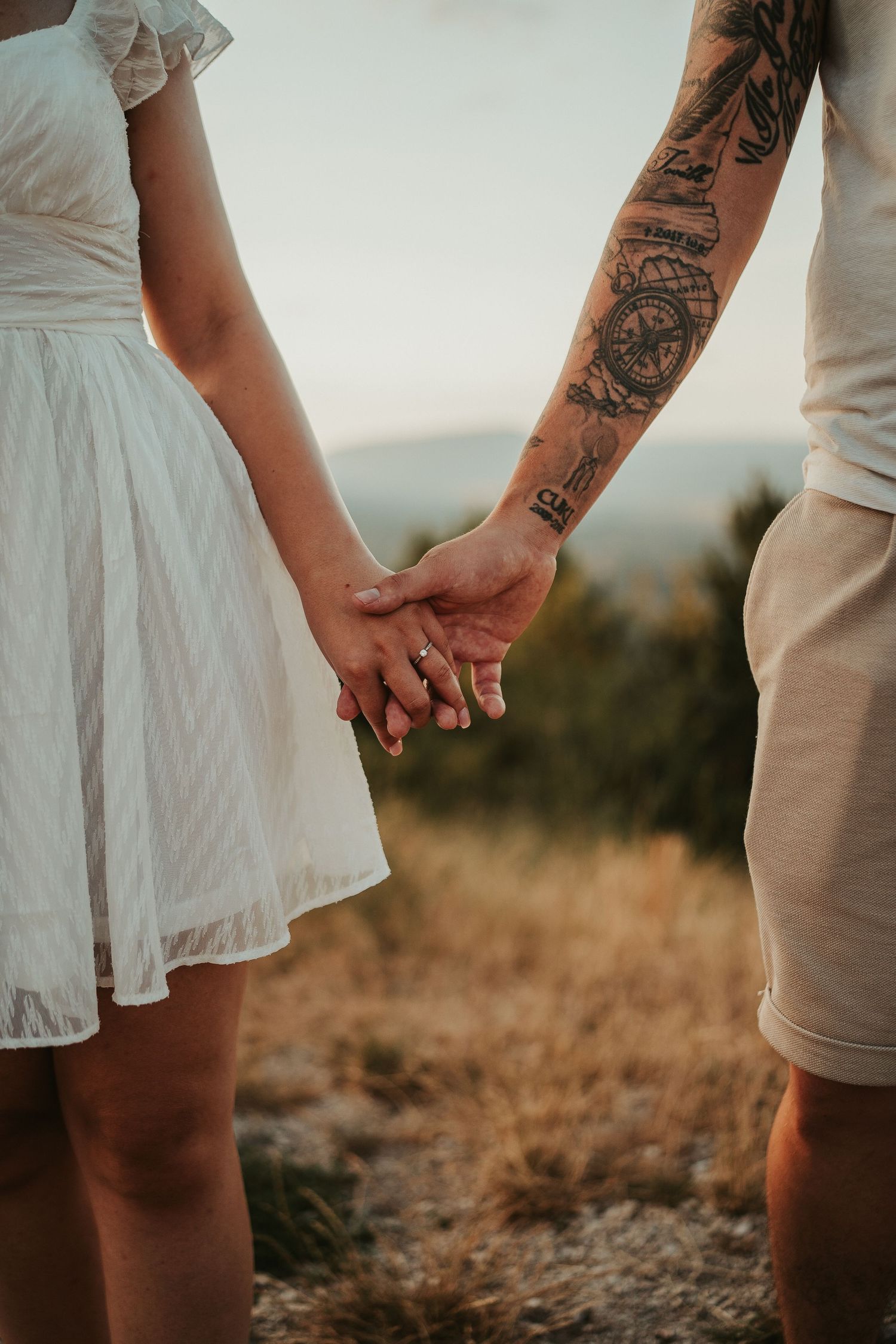 Close-up of couple holding hands with one person showing detailed arm tattoo.