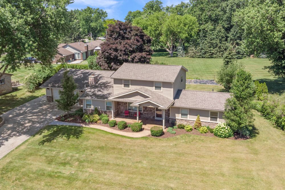 Aerial view of spacious two-story home with red porch columns, attached garage, and green lawn.