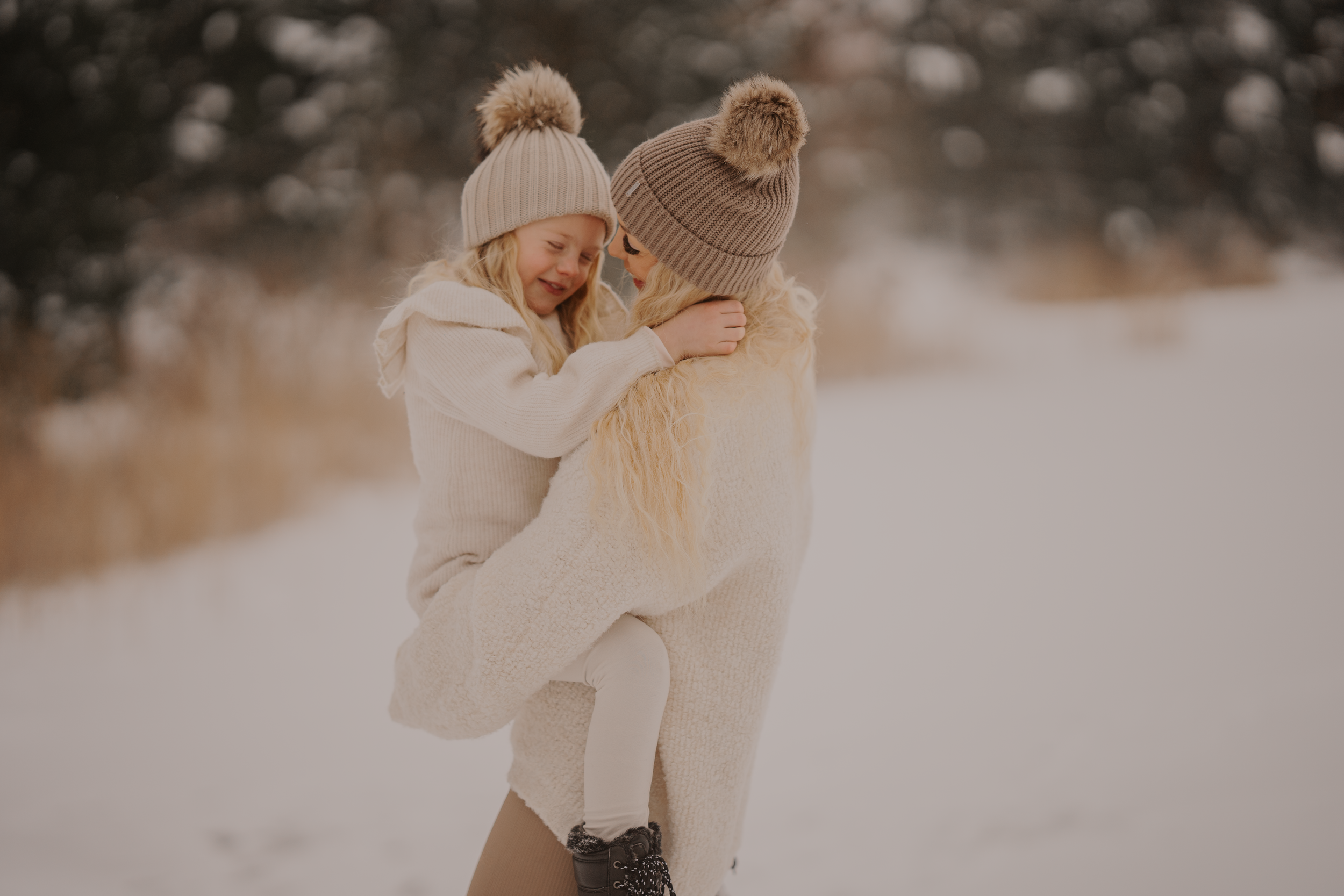 Two people in winter clothing sharing a playful embrace in a snowy landscape.