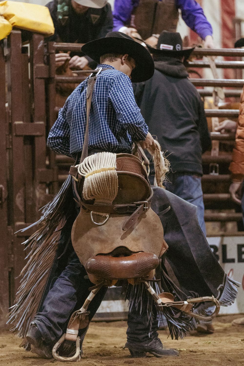 Rider in traditional western gear mounted on a horse during indoor rodeo competition.