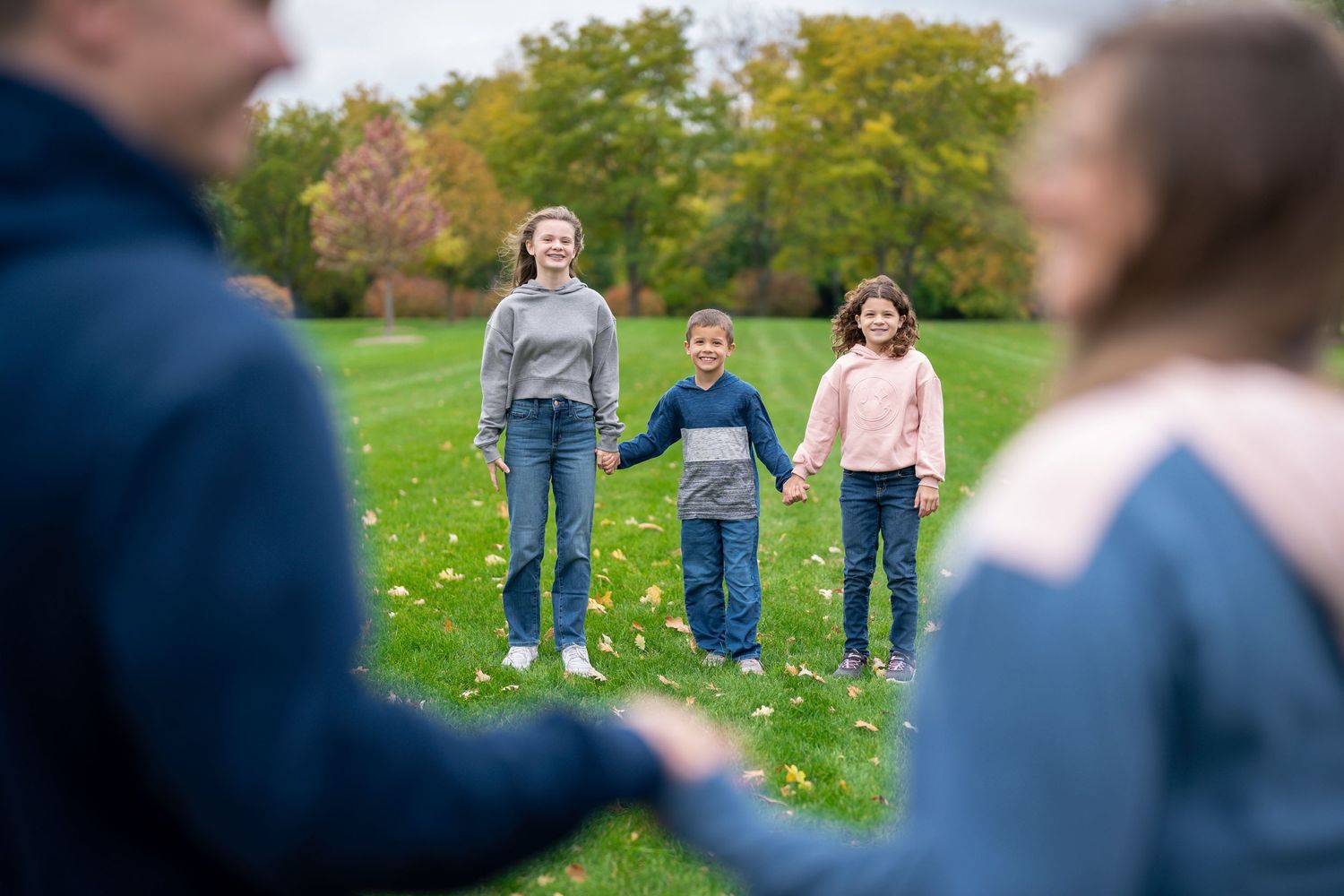 Family members standing together on grassy hill during fall photo session.