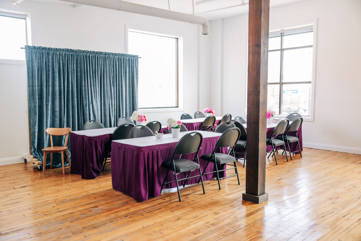 Modern event room with purple-draped tables and blue curtain partitions.