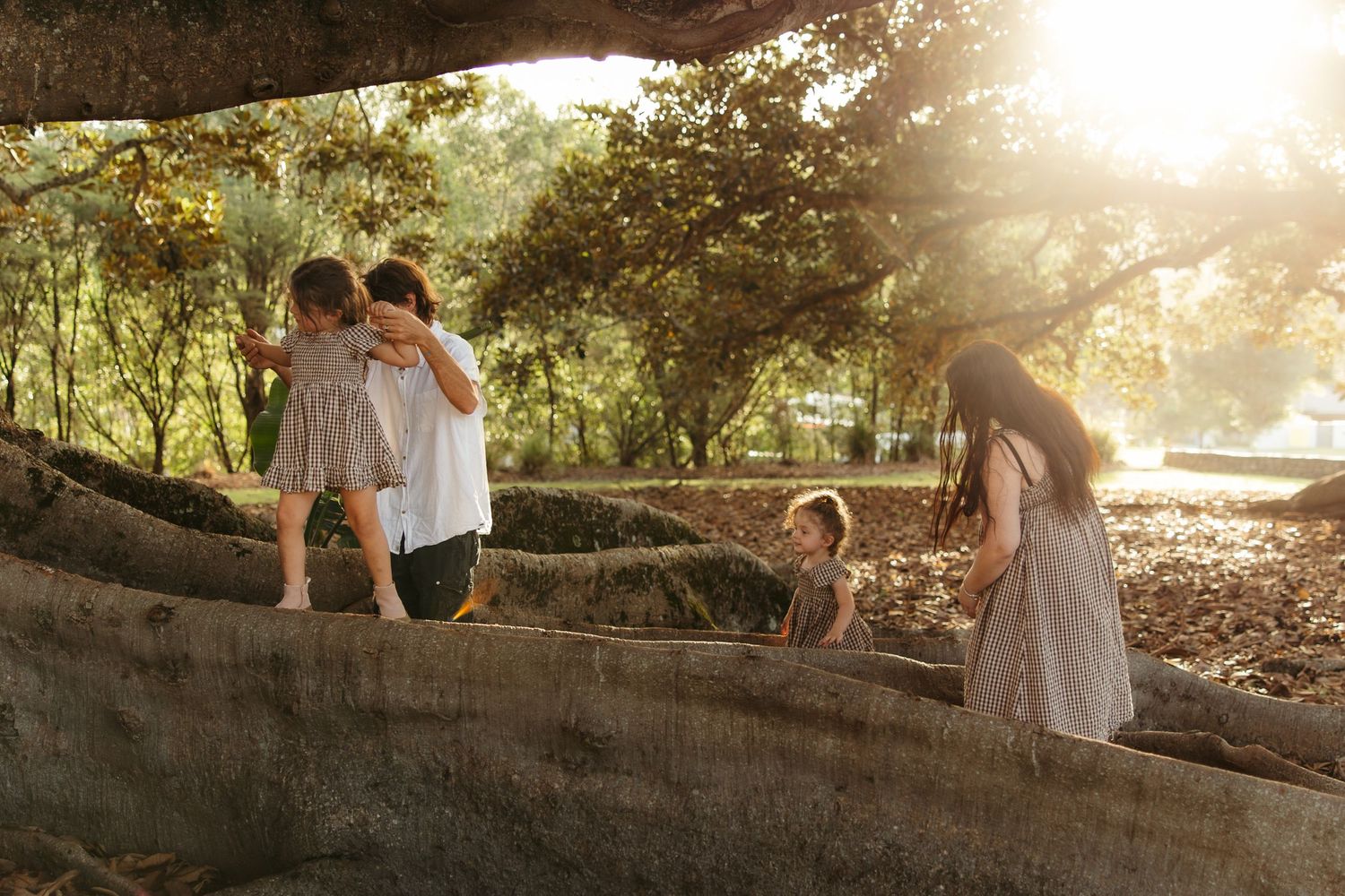 A playful moment captured outdoors under trees with laughter and joy between loved ones on a sunny afternoon.
