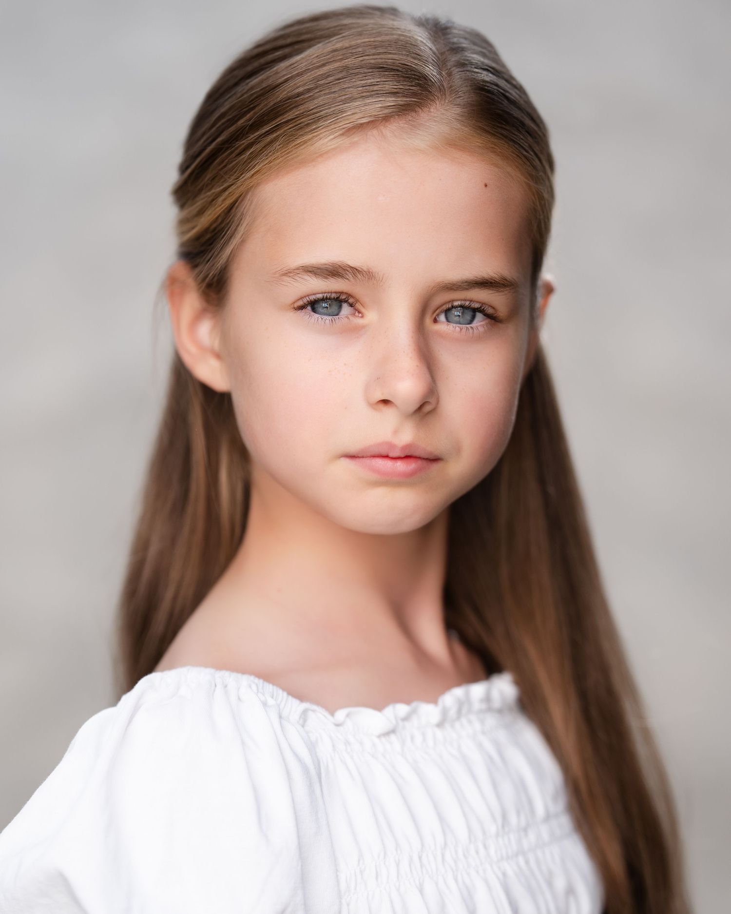 Professional headshot of person with long brown hair wearing light colored top in Guildford, Surrey.