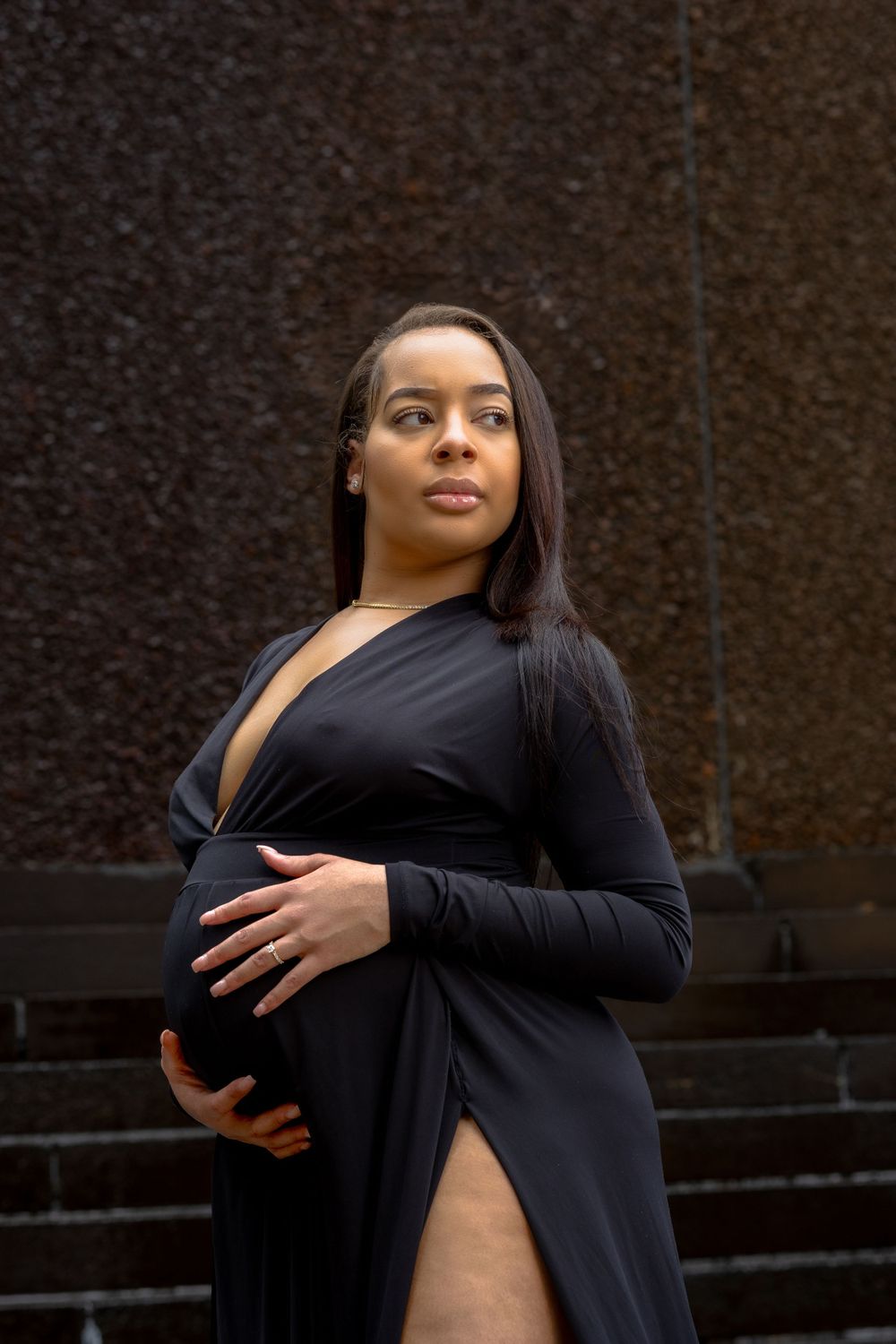 Elegant maternity portrait of someone in a black formal dress with thigh-high slit.
