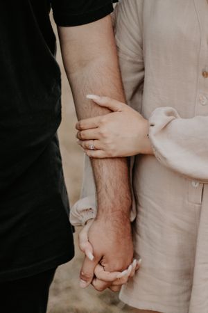 Close up of a couples arms showcasing an engagement ring.