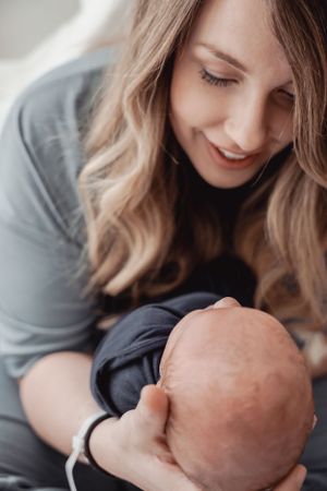 A mother in a gray sweater lovingly holds and gazes at her newborn baby in a series of tender black and white photos.