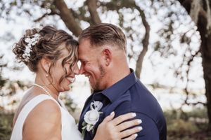 Romantic wedding couple embraces outdoors during intimate ceremony in natural setting.