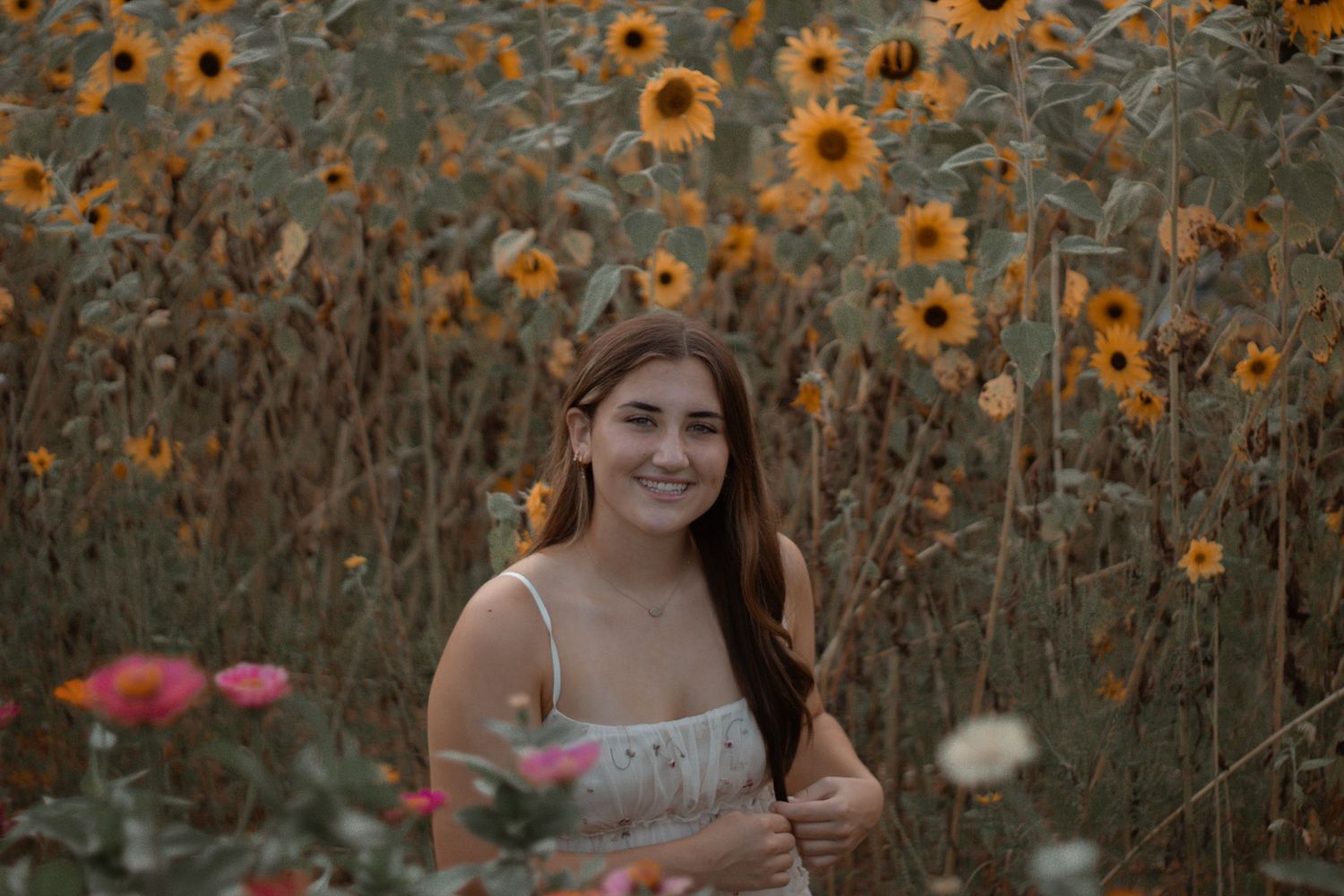 Portrait in sunflower field with golden evening light creating dreamy atmosphere.