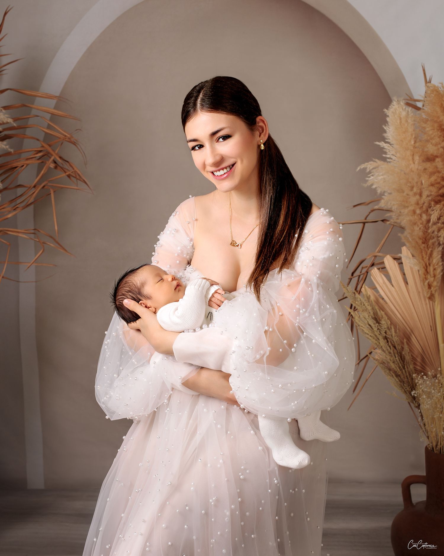 mother smiling holding newborn baby boy, mother in couture pearl gown by Caz Captures Sydney Photographer