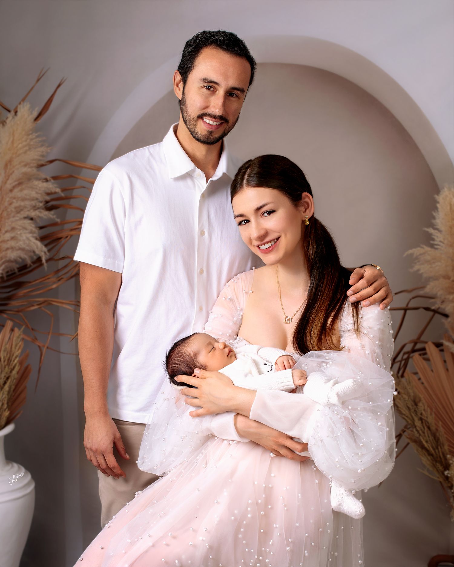 mother and father together smiling holding their newborn baby boy, mother in couture pearl gown by Caz Captures Sydney Photographer