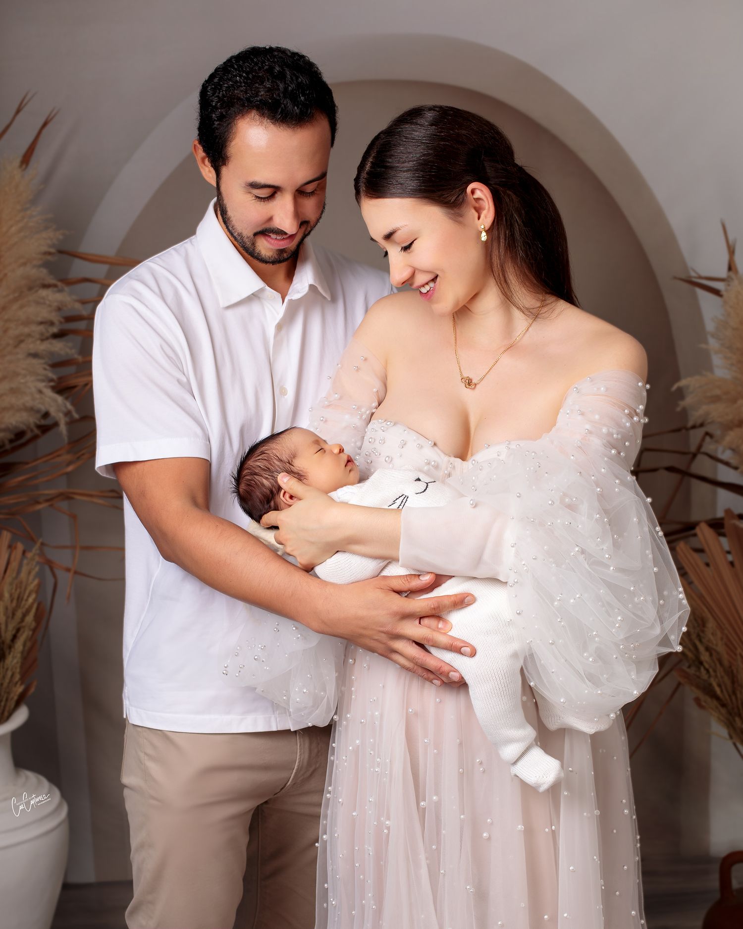 mother and father together smiling holding their newborn baby boy, mother in couture pearl gown by Caz Captures Sydney Photographer