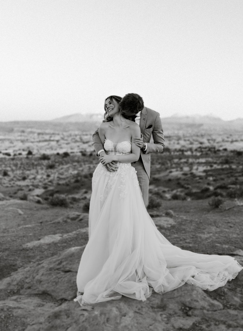 An intimate black and white wedding portrait captured in a desert setting.