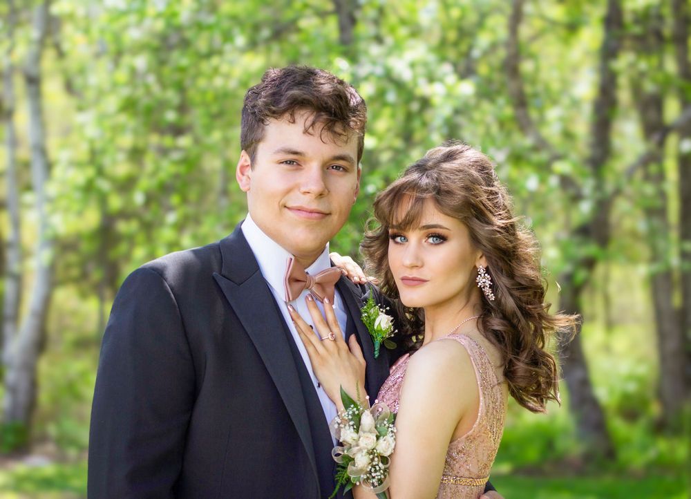 Natural light prom portrait photography of a couple smiling at the camera with green trees in the background