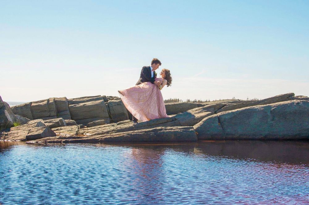 Dramatic photo of a posed prom couple across the water in Yarmouth, Nova Scotia, by Daneesha Williams