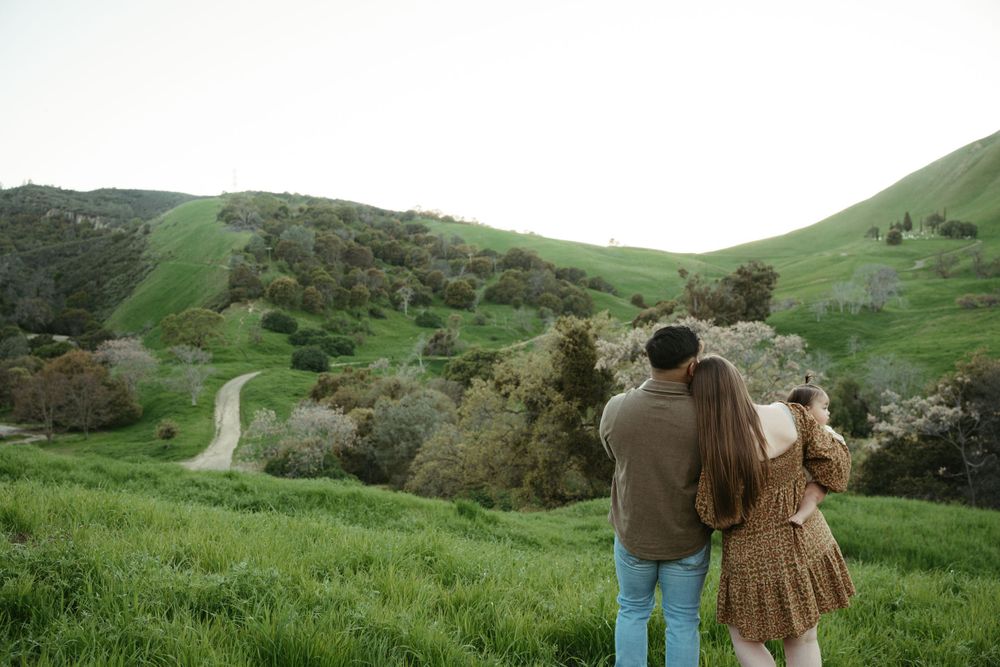 Couple admiring scenic view of rolling green hills and winding path from hilltop at Antioch, CA.