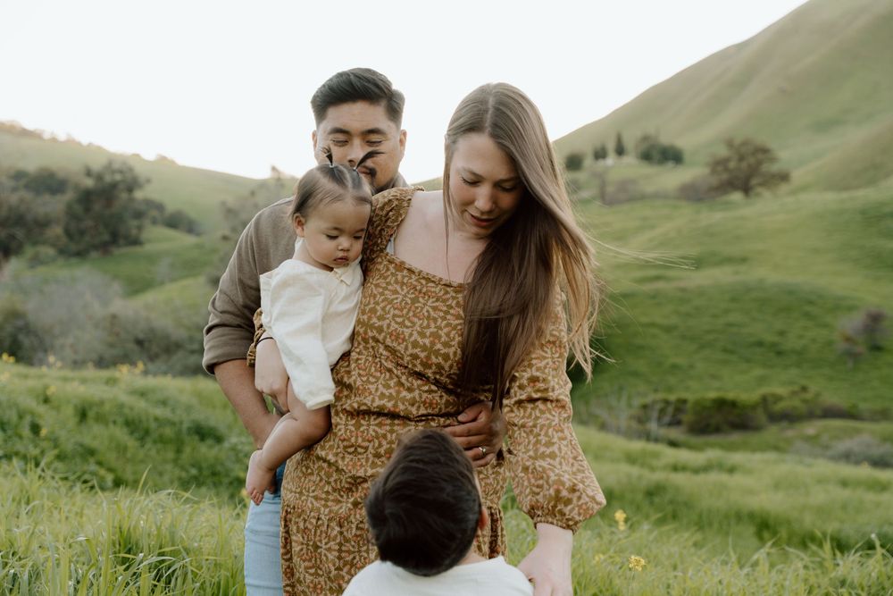 Family sharing a candid moment together in a scenic hillside meadow at Antioch, CA.